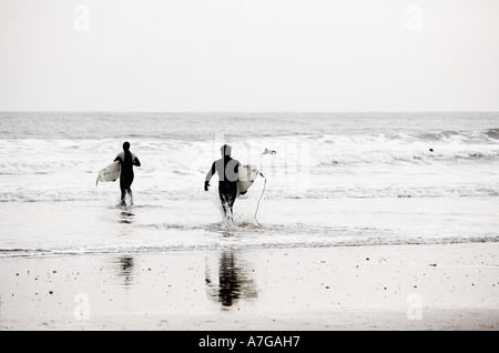 Surfers sur une plage en hiver froid England UK Banque D'Images