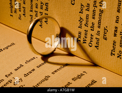 Anneau de mariage jette une ombre en forme de coeur sur un livre de poésie Banque D'Images