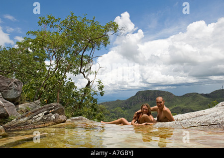 Un couple de touristes vous détendre dans une formation rocheuse qui créent des piscines naturelles d'eau dans la Chapada dos Veadeiros National Park. Banque D'Images