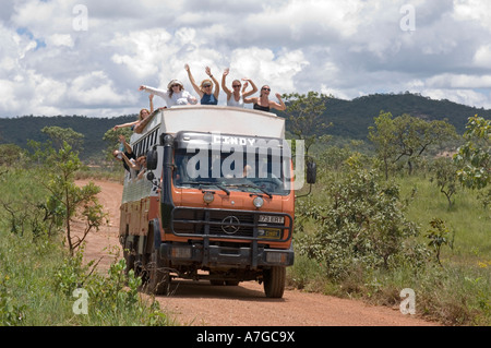 Une maison de l'aventure terrestre camion avec heureux touristes forme tout en voyageant le long d'un chemin de terre en direction de Brasilia. Banque D'Images