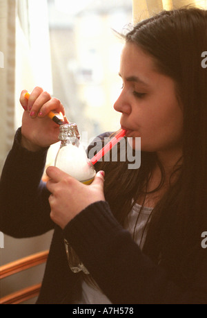 Jeune femme fumeurs de crack des roches à partir d'un tuyau d'eau fait maison. Banque D'Images