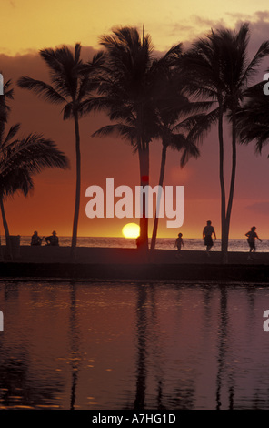 N.A., USA, Hawaii, Big Island, les gens sur la plage sous les palmiers au coucher du soleil, et le lagon à l'Anaeho'omalu Bay Banque D'Images