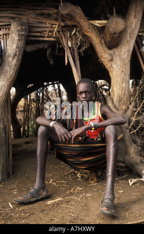 Les Karimojong garçon par la cabane dans un village à la base du mont Kadam 3068m, Karimoja, Ouganda Banque D'Images