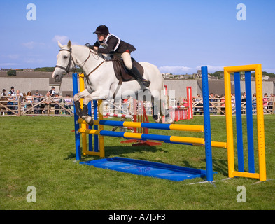 dh County Show KIRKWALL ORKNEY White Pony Horse Jumping événement sur la clôture de terrain anneau fille royaume-uni saut arène adolescents sport adolescent Banque D'Images