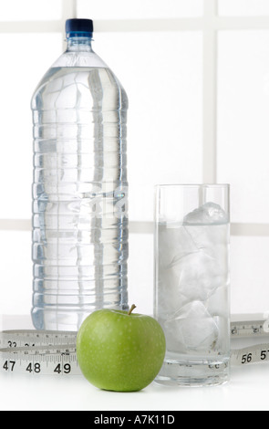 PORTRAIT D'UNE BOUTEILLE D'EAU AVEC UN VERRE D'EAU ET UNE POMME avec un ruban à mesurer Banque D'Images