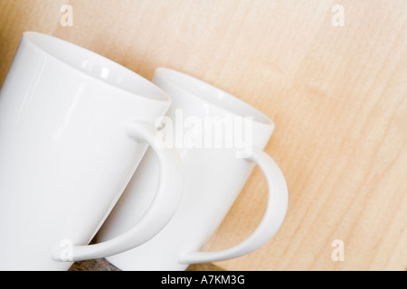 Deux tasses blanc sur un compteur contre un mur en bois Banque D'Images