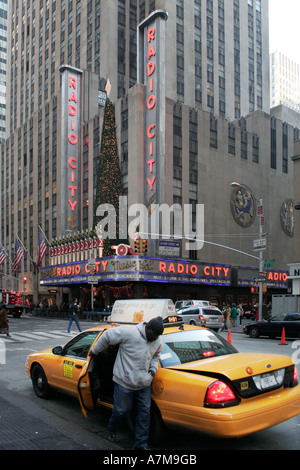 Un homme sortir d'un taxi jaune en face de la Radio City Music Hall. La ville de New York. USA. Saison de vacances de Noël. Banque D'Images