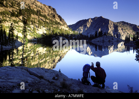 Randonneur au coucher du soleil avec vue sur le lac Miroir dans l'Eagle Cap désert, de l'Oregon. Banque D'Images