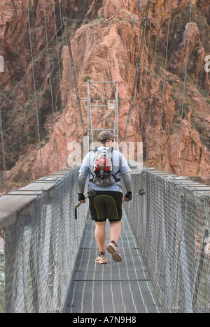 Un randonneur traverse le pont d'argent sur le fleuve Colorado à la fin de la Bright Angel Trail dans le Grand Canyon Banque D'Images