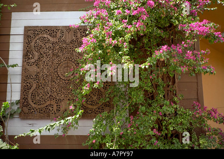 Sculpture sur bois complexes sur un jardin avec mur chalet bougainvilliers en fleurs. Mayang Sari Beach Resort, Bintan Island, Indonésie. Banque D'Images