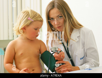 À l'intérieur du cabinet ambulatoire mature femme fille enfant 30 35 510 lunettes blondes blonde corps médecin pédiatre sit patient gow Banque D'Images