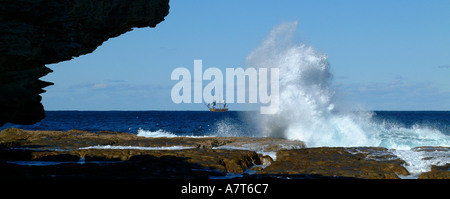 La plage de Bondi vagues contre des rochers qui s'affrontent avec tale dans la distance du navire à Sydney Austraila Banque D'Images