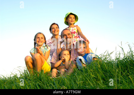 Family sitting in field Banque D'Images