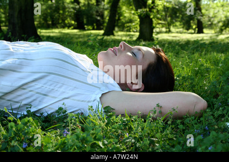 Young woman lying on meadow, side view Banque D'Images