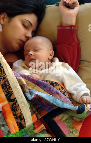 Mère hispano-américaine et deux (2) mois faire une sieste sur le canapé. Banque D'Images