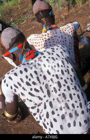 Un guerrier Karo carrosserie peinture met sur un autre homme près de leur village en Éthiopie dans la région de la rivière de l'Omo, l'Afrique. Banque D'Images