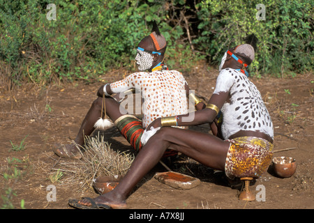 Un guerrier Karo carrosserie peinture met sur un autre homme près de leur village en Éthiopie dans la région de la rivière de l'Omo, l'Afrique. Banque D'Images