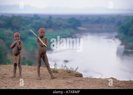 Deux jeunes garçons Karo debout sur une corniche surplombant la rivière Omo, juste à l'extérieur de leur village en Éthiopie, en Afrique. (MR) Banque D'Images