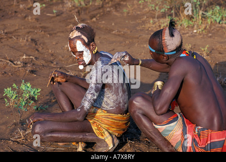 Un guerrier Karo carrosserie peinture met sur un autre homme Karo, l'Éthiopie dans la région de la rivière Omo, en Afrique. Banque D'Images