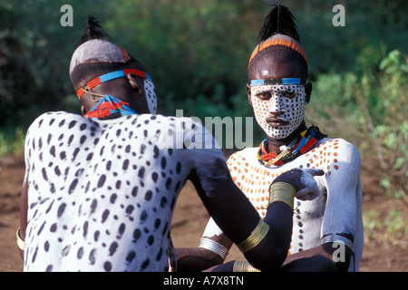 Un guerrier Karo carrosserie peinture met sur un autre homme Karo, l'Éthiopie dans la région de la rivière Omo, en Afrique. Banque D'Images