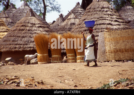 Une femme porte Bedik une grande baignoire bleu sur sa tête à travers le village de Iwol, au Sénégal, l'Afrique. Banque D'Images