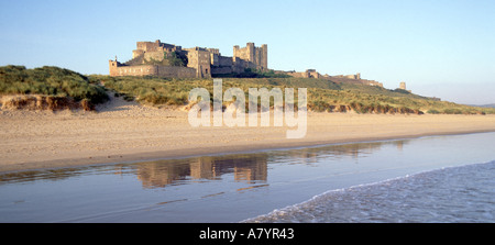 Le paysage côtier historique du château de Bamburgh reflète dans la plage de sable eau marémotrice et dunes de sable pittoresque Northumberland littoral de la mer du Nord Angleterre Royaume-Uni Banque D'Images