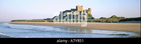 Le paysage côtier historique du château de Bamburgh reflète dans la plage de sable eau marémotrice et dunes de sable pittoresque Northumberland littoral de la mer du Nord Angleterre Royaume-Uni Banque D'Images