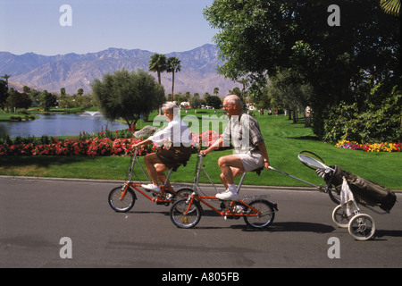 Vieux couple cycliste à Palm Springs en Californie avec des raquettes de tennis en sac de golf Banque D'Images