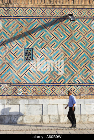 Homme marchant passé mur décoratif de Tilla-Kari Medressa Registan à Banque D'Images