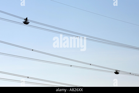 Examiner les lignes d'alimentation des travailleurs silhouetté contre le ciel, Cambridgeshire, Angleterre Banque D'Images