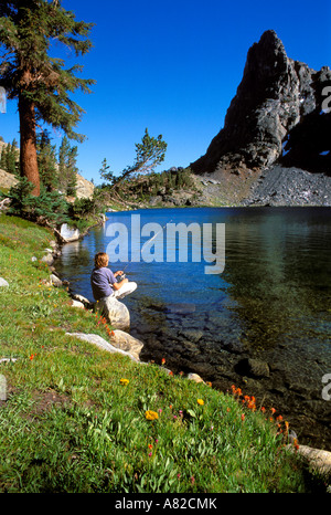 Jeune randonneur la pêche sur la rive du lac Minaret Ansel Adams Wilderness Sierra Nevada en Californie Banque D'Images