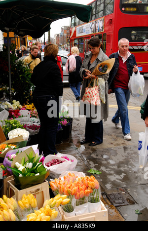 Femme achetant des fleurs à un stand de fleurs, faisant du shopping, bus à impériale rouge. Kings Road, Chelsea, Londres Angleterre HOMER SYKES Banque D'Images