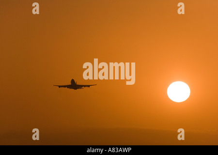 Un jet décolle de l'Aéroport International de Los Angeles au coucher du soleil. Banque D'Images