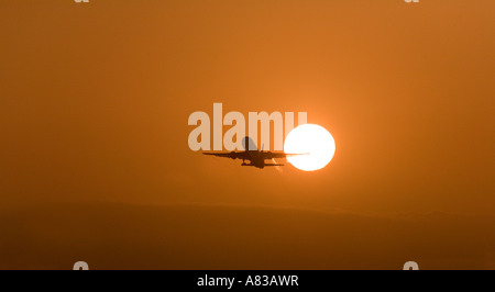 Un jet décolle de l'Aéroport International de Los Angeles au coucher du soleil. Banque D'Images