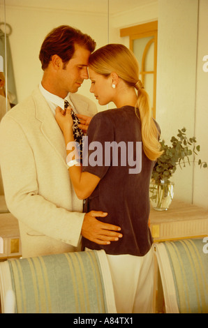 Jeune couple à l'intérieur. Redressage de la cravate homme femme. Banque D'Images
