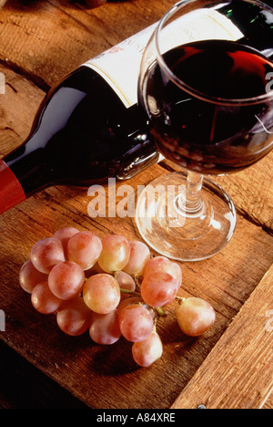 Still Life close-up de verre de vin rouge et une bouteille avec des raisins sur table. Banque D'Images