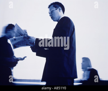 Piscine close-up side view of Chinese man reading newspaper. Banque D'Images