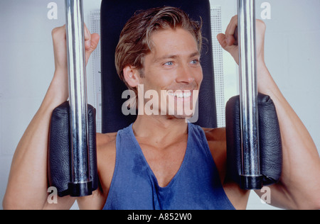 Portrait de jeune homme à l'intérieur en utilisant l'équipement d'exercice dans un gymnase. Banque D'Images