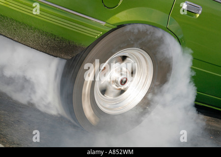 Close up de la fumée s'échapper d'un pneu de voiture faisant un burnout avant une course de glisser Banque D'Images