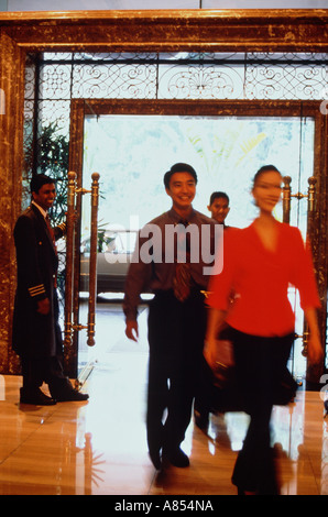 Jeune couple arrivant à l'hôtel, être accueilli par portier dans le hall. Banque D'Images