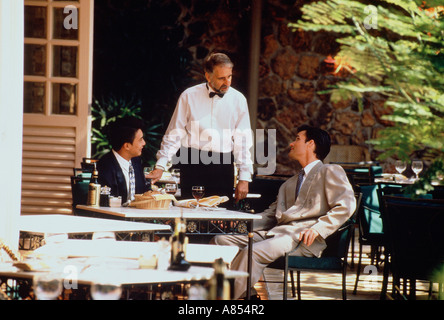 Deux hommes assis à table en terrasse d'un café en parlant avec serveur. Banque D'Images