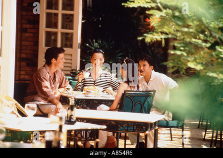 Quatre amis assis sur une terrasse de café restaurant. Singapour Banque D'Images