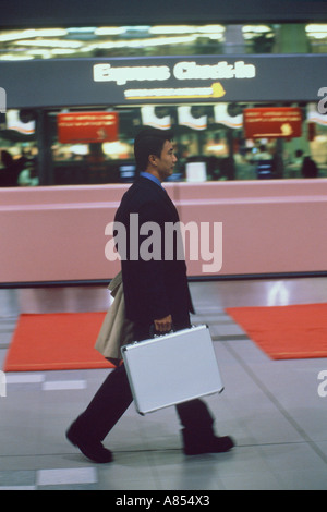 L'homme d'affaires à l'intérieur de terminal de l'aéroport à pied par l'arrivée d'un bureau. Banque D'Images