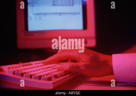 Close up of main sur clavier de l'ordinateur avec l'écran du moniteur. Banque D'Images