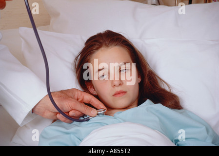 Close-up de l'enfant malade à l'hôpital lit avec main de doctor holding stethoscope à sa poitrine. Banque D'Images