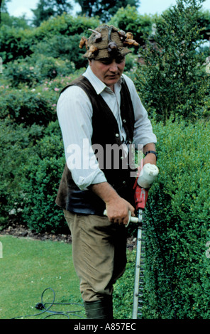 Découpage d'un jardinier professionnel fort haie avec un taille-haie électrique, Hatfield House, Hertfordshire, England, UK. Banque D'Images