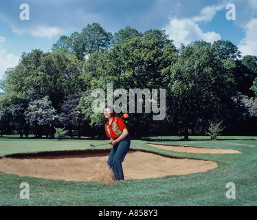 Le sport. Loisirs de l'établissement. Jeune femme jouant au golf. Ébrécher la balle d'un bunker de sable. Banque D'Images