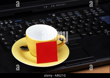 Espresso cup jaune rouge avec des post-it sur le clavier d'un ordinateur portable noir Banque D'Images
