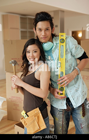 Jeune couple avec un marteau et un niveau à bulle, portrait Banque D'Images