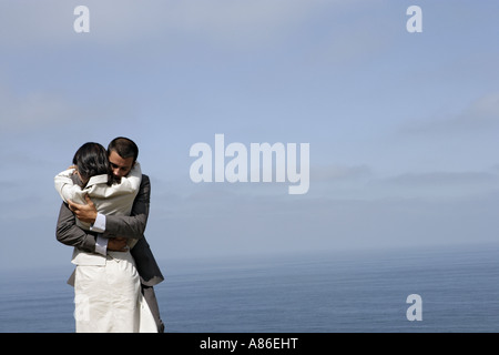 Vue d'un couple hugging les uns les autres sur une falaise. Banque D'Images